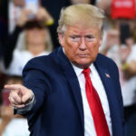 Man in suit pointing at crowded event