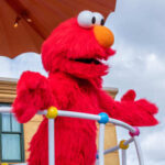 Elmo character on a parade float under an umbrella