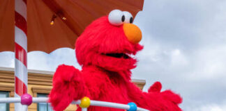 Elmo character on a parade float under an umbrella