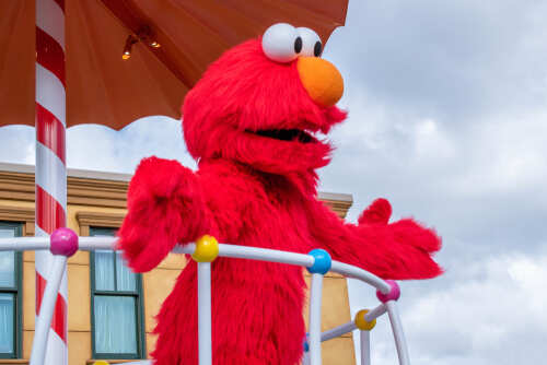 Elmo character on a parade float under an umbrella