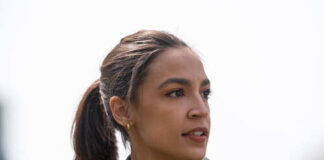 A woman with a ponytail wearing a leather jacket, looking thoughtfully into the distance