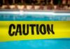 Yellow caution tape in front of a swimming pool