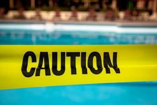 Yellow caution tape in front of a swimming pool