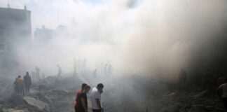 People standing amidst smoke and debris after a disaster