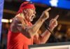 A muscular man in a red bandana passionately speaking at a podium