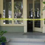 A front porch with caution tape indicating a crime scene