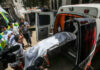 People loading stretcher into ambulance surrounded by onlookers