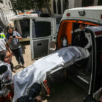 Turks and Caicos Mass Shooting Leaves 3 Dead, Gang Ties Suspected People loading stretcher into ambulance surrounded by onlookers