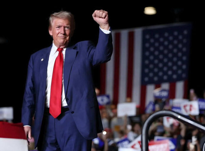 Man in suit raises fist at event with crowd