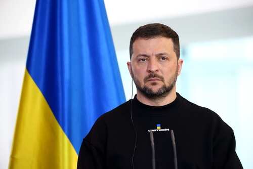 A political leader standing in front of a Ukrainian flag during a press conference