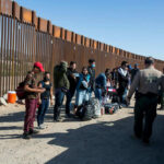 Trump’s Immigration Policy: Cruel Reality or Necessary Action? People at border fence with patrol officers present