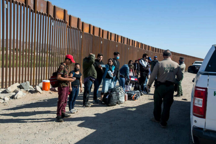 People at border fence with patrol officers present