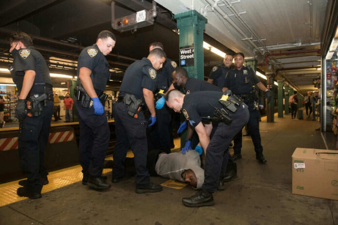 Police officers detaining person on subway platform