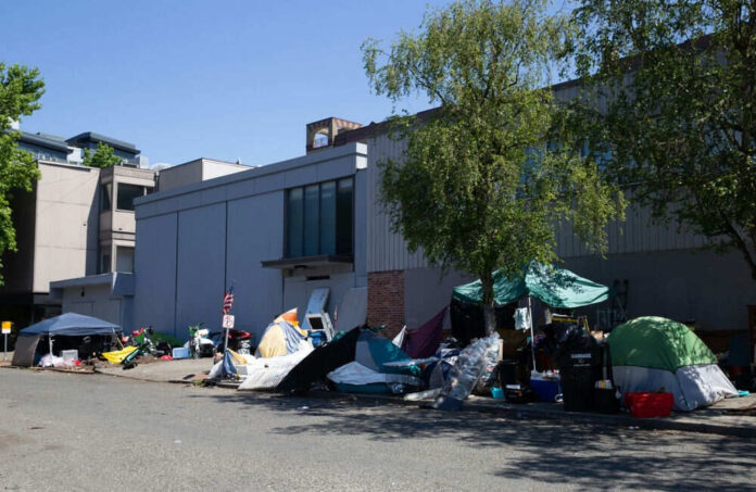 Tents and belongings on a street beside buildings