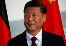 Person in suit with red and black flags behind