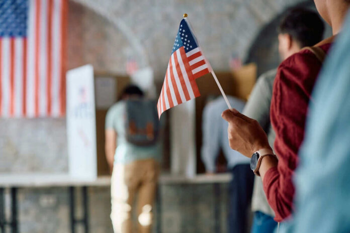 People voting and holding a US flag indoors