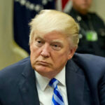 Man in suit with blue striped tie seated
