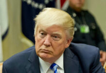Man in suit with blue striped tie seated