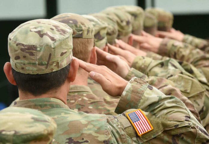 Soldiers saluting in camouflage uniforms with flag patches