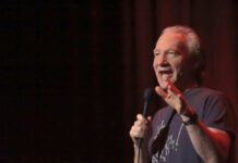 Person holding microphone on stage in dark setting