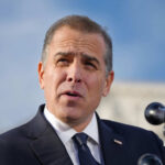Man speaking outside with microphones in foreground