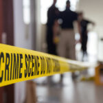 Deadly Campus Failure Exposes “Safe School” Myth Yellow crime scene tape with blurred figures in the background
