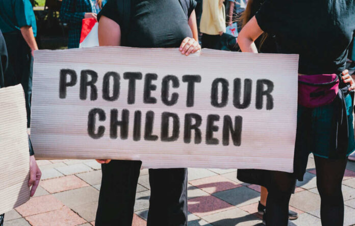 Person holding sign reading Protect Our Children