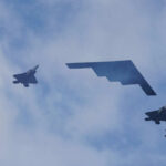Five military aircraft flying in formation under clouds