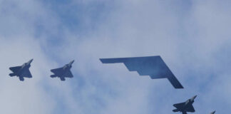 Five military aircraft flying in formation under clouds