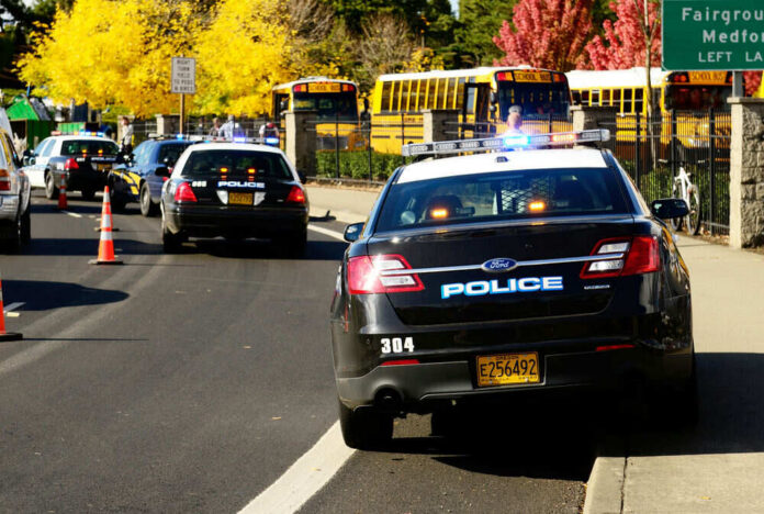 Police cars and school buses on roadside with cones