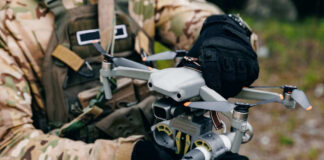 Person holding drone in camouflage uniform and gloves