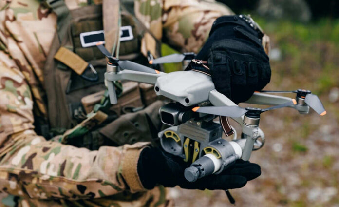 Person holding drone in camouflage uniform and gloves